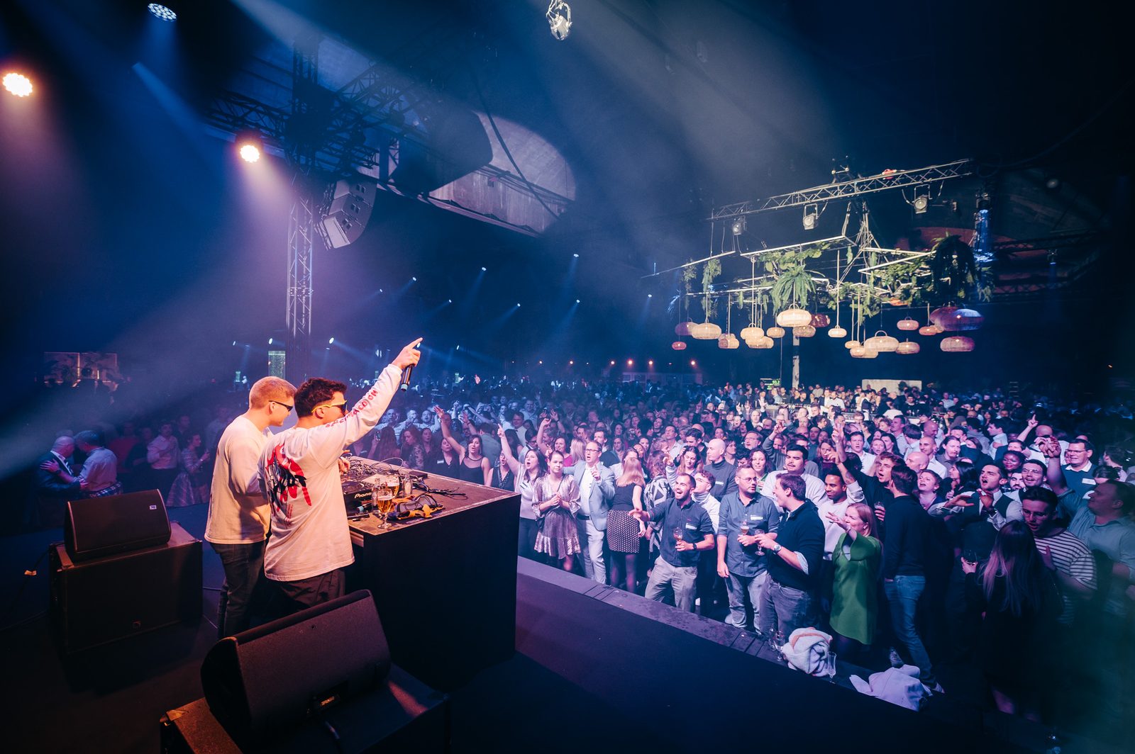 Dj's op het podium voor een volle dansvloer met lichtbundels