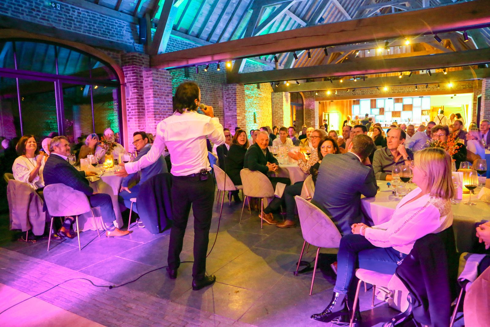 Zanger tussen de tafels in een feestzaal met houten balken