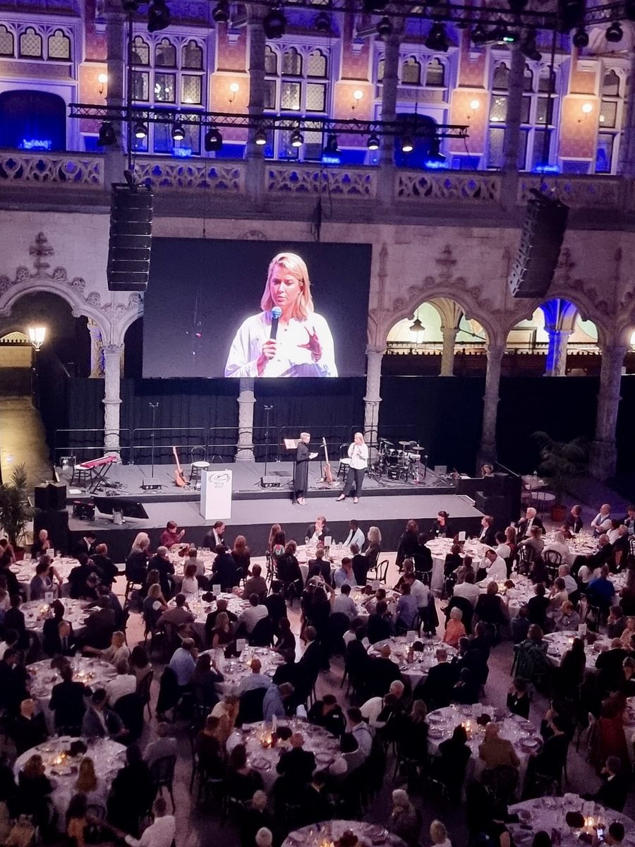 Galadiner van Mercy Ships in een historische zaal, met een spreker op het grote scherm